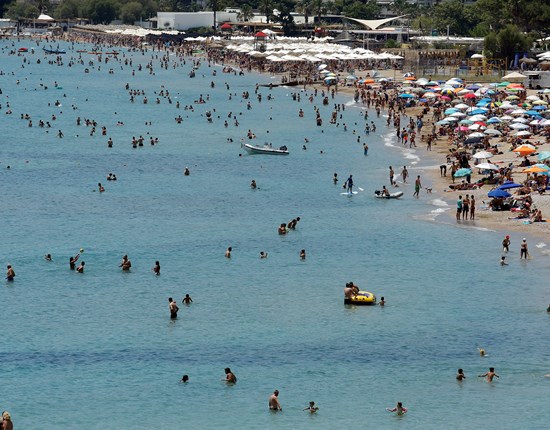 Mensen zwemmen in zee en liggen op druk bezocht strand