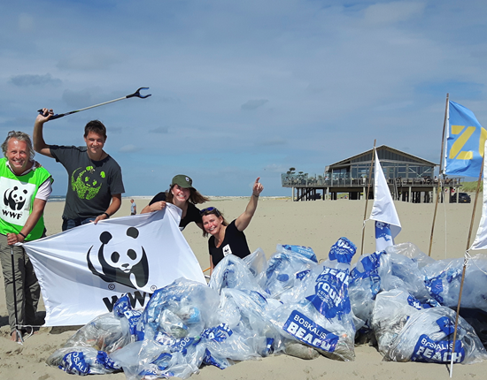 mensen met wwf logo staan naast afval op strand